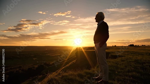 A contemplative senior man, silhouetted against a radiant sunset, standing on a grassy hillside, gazing thoughtfully at the horizon, embracing the golden hour's tranquil beauty and reflectin