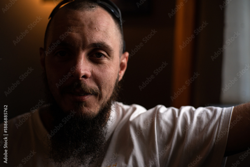 Obraz premium Man with beard looks out a window while sitting in bar in soft light during the day