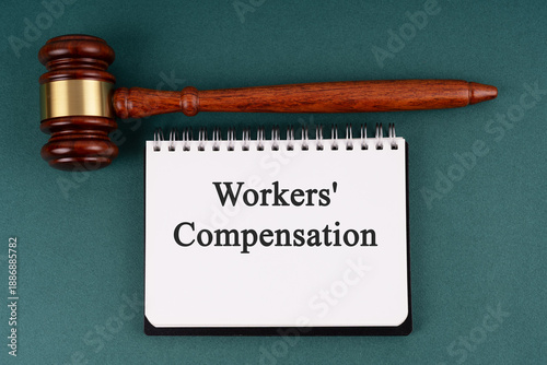 Gavel and notepad with text workers compensation on green background