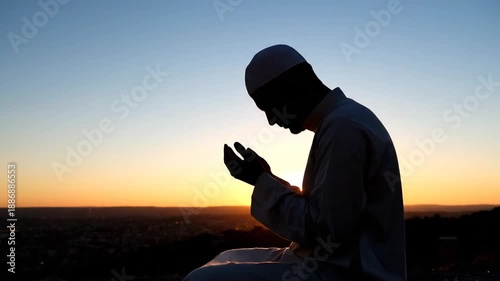 A man praying in solitude at sunset on a hill, captured in a serene video landscape