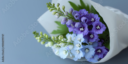 Delicate bouquet of blue and purple delphinium flowers wrapped in white paper