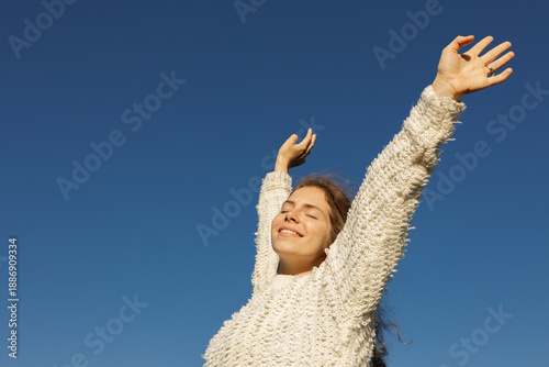 freedom-loving, happy young European woman in her twenties enjoys moment standing in sun under a cloudless sky. I love life, well-being, positive thinking, and dreaming. Walking in spring outdoors