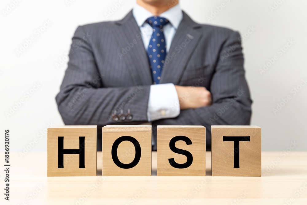 Obraz premium 「HOST 」と書かれたブロックと腕組みをするビジネスマン