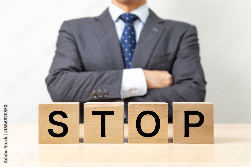 Obraz premium 「STOP 」と書かれたブロックと腕組みをするビジネスマン