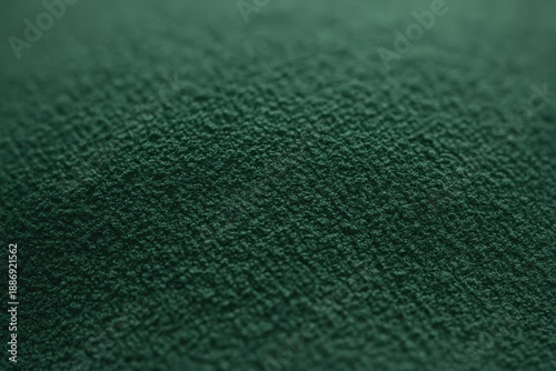 A close-up view of deep-green nickel oxide powder with a fine, velvety granular texture, forming a softly undulating surface