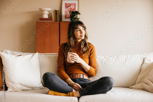 Fotografija Woman enjoying a cozy moment of relaxation, holding a mug and looking away while