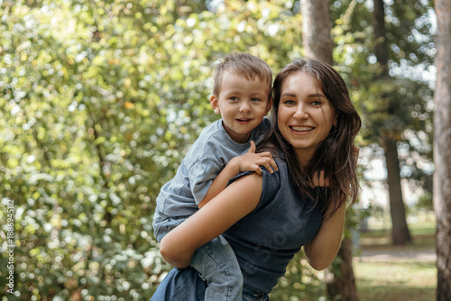 A happy young mother plays and has fun with her little son outdoors in a park. The mother talks to her baby. The concept of a happy family and motherhood. 