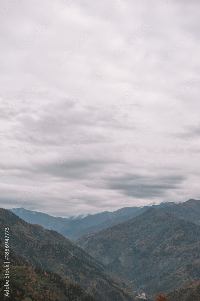 Fototapeta premium Autumn mountains stretch across dramatic valley under clouds