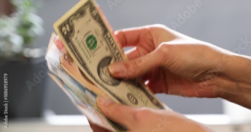 Woman counting United States dollar banknotes with various international currencies held in her hands for financial exchange