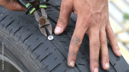 Hand removing a nail from a flat tire
