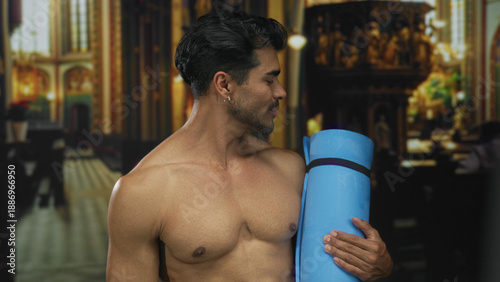 Foto Man with bare chest holds blue yoga mat inside building while smiling broadly; irreverence defiance
