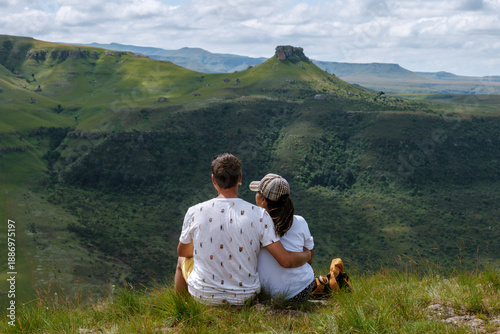 Fotografie A couple relaxes in the lush greenery of Drakensberg Mountain, gazing at breathtaking landscapes