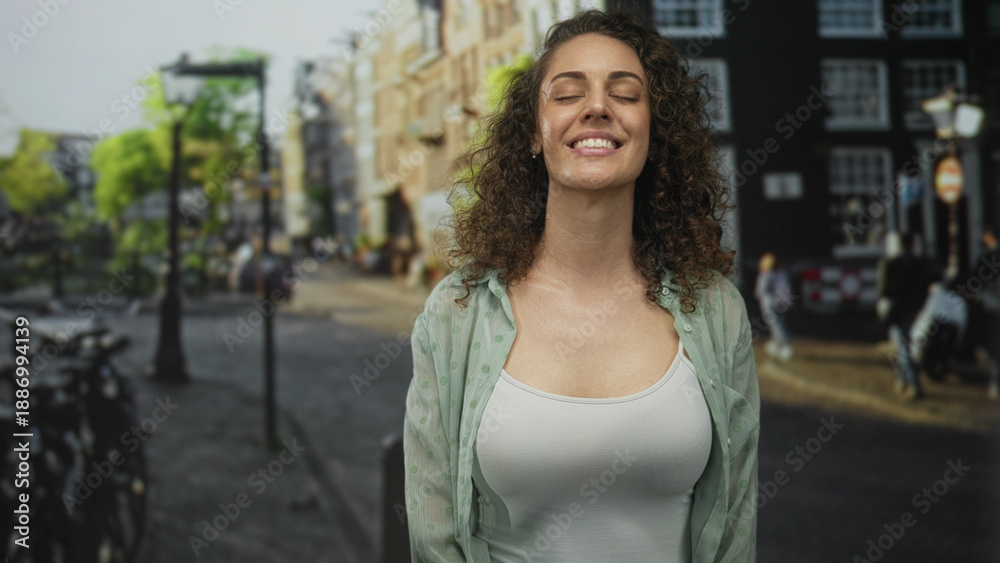 Fototapeta premium Woman smiling with eyes closed, wearing open shirt and white tank showing bare chest on a street with bicycles and lamp posts; calm contentment.