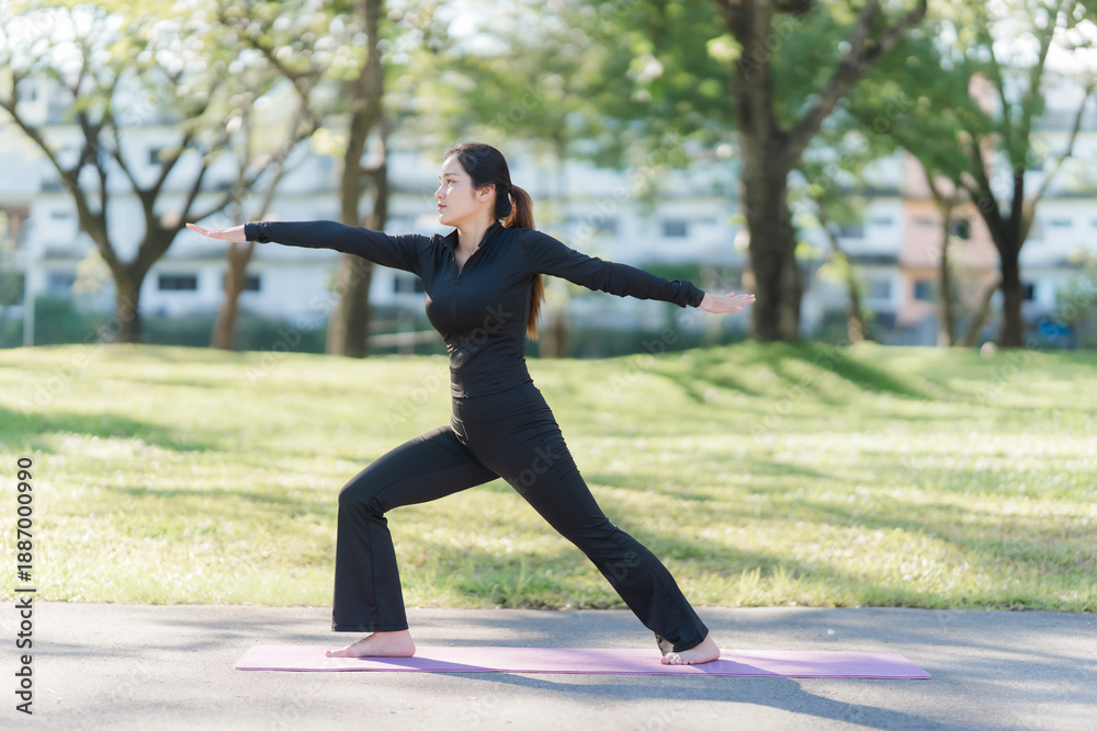 Fototapeta premium Balance in Nature: An individual practices a warrior yoga pose amidst the embrace of nature, surrounded by trees and vibrant greenery, promoting holistic well-being.