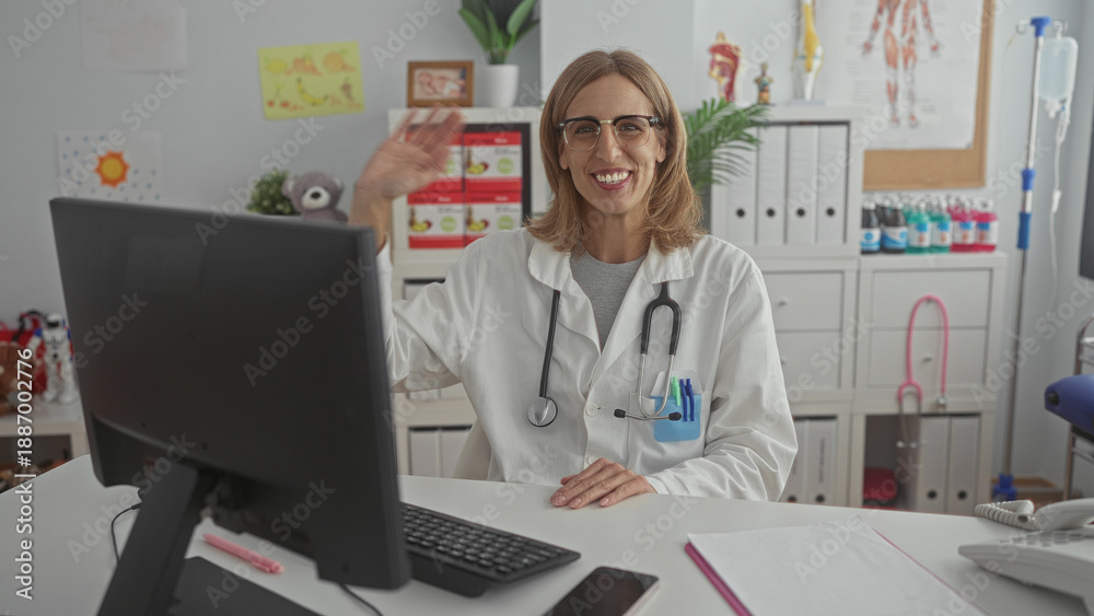 Obraz premium Woman pediatrician in white coat waves hand with stethoscope at computer in clinic building; reassurance friendly care.