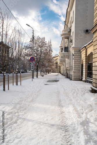 Winter city street. Roads and sidewalks are covered with snow. A sunny January day. After a heavy overnight snowfall. New Year's Morning. Old houses. An empty road.