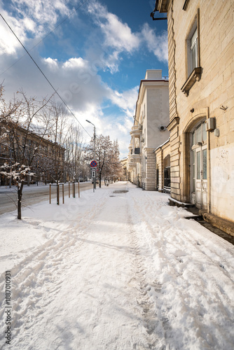 Winter city street. Roads and sidewalks are covered with snow. A sunny January day. After a heavy overnight snowfall. New Year's Morning. Old houses. An empty road.