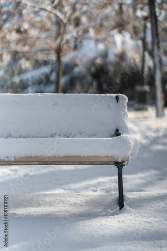 Winter city Park. The sidewalk, bench and trees are heavily covered with snow. A sunny January day. After a heavy overnight snowfall. New Year's Morning.