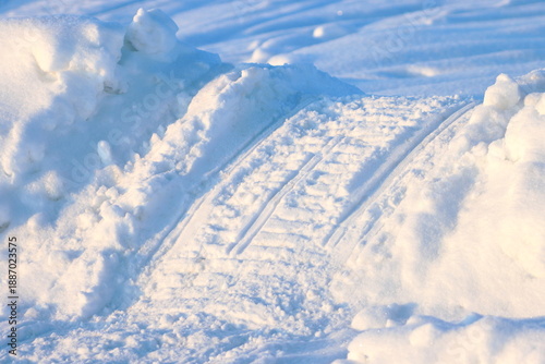 A snowmobile track in the snow at the side of the road