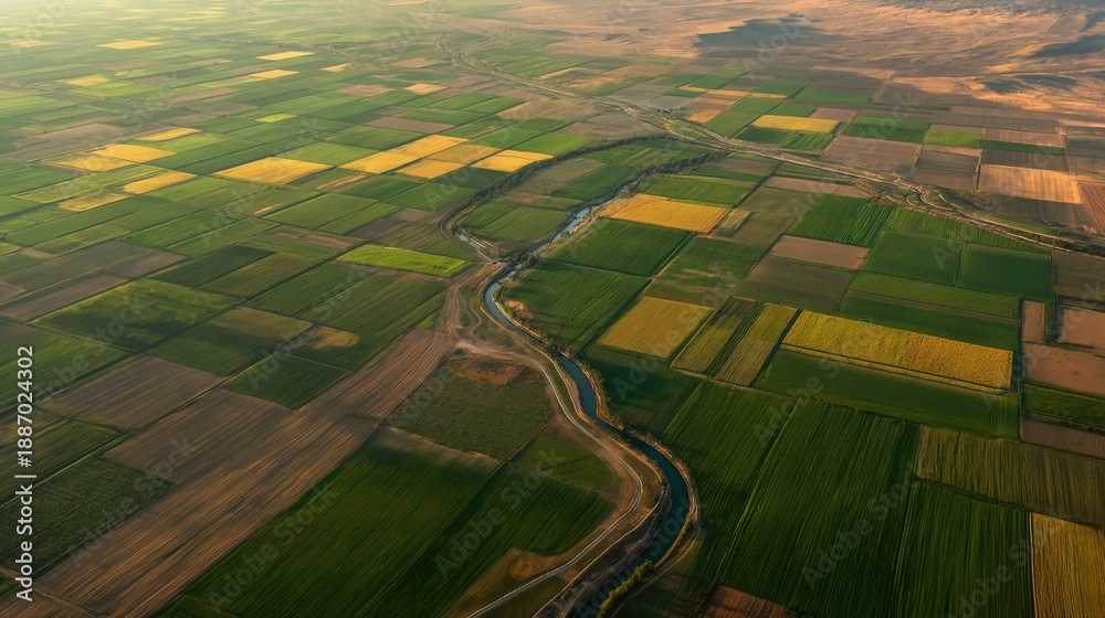 Fototapeta premium High altitude aerial view of colorful patchwork farmland with geometric crop fields divided by irrigation canal and rural roads