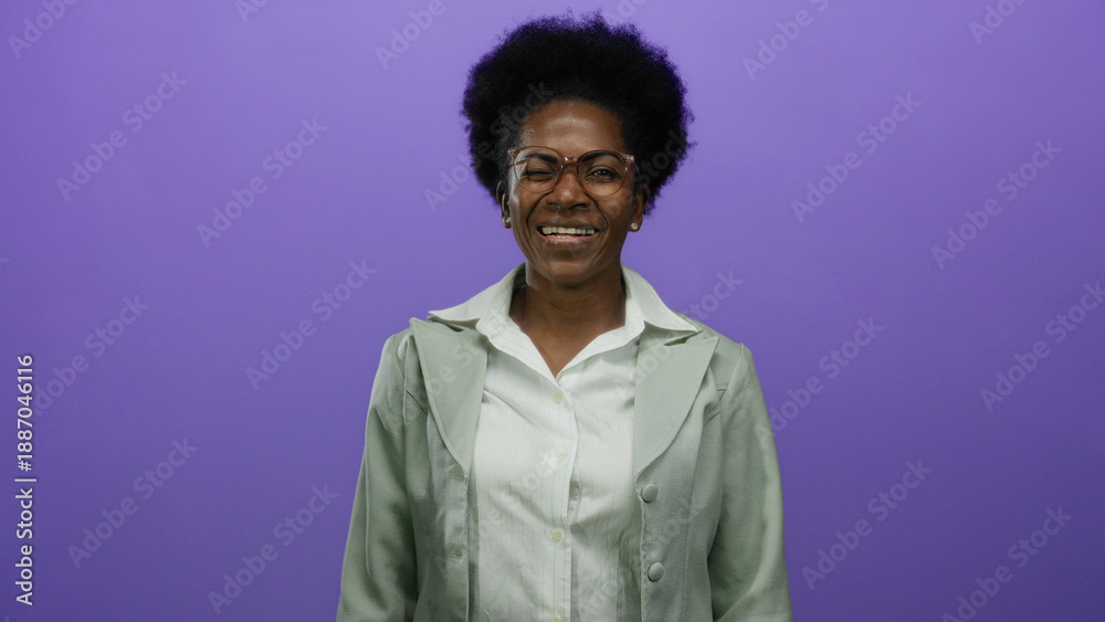 Obraz premium Woman smiling in front of an isolated purple background wearing glasses and a light green jacket exhibiting joy and confidence with a natural expression of happiness and enthusiasm.