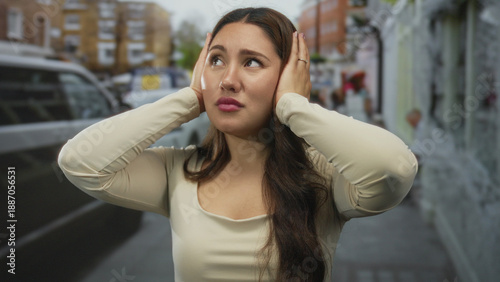 Foto Young hispanic woman covers ears with hands amid honking traffic on a busy city street; stress anxiety overload