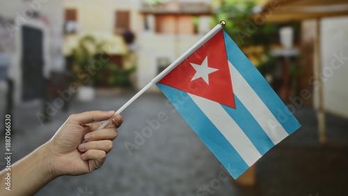 Bilde på lerret Man holding a cuban flag in an outdoor city street scene, showcasing national pride and cultural identity with a blurred urban background emphasizing location