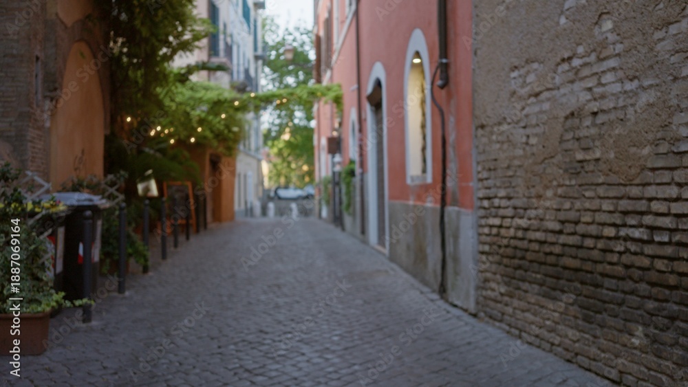 Fototapeta premium Sunlit narrow cobblestone alley with textured brick walls, hanging vines and distant cafe lights in soft bokeh; background backplate copyspace calm.