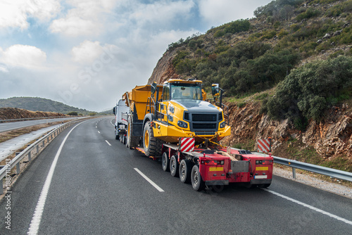 Special transport truck carrying large construction machinery on a trailer, rear view