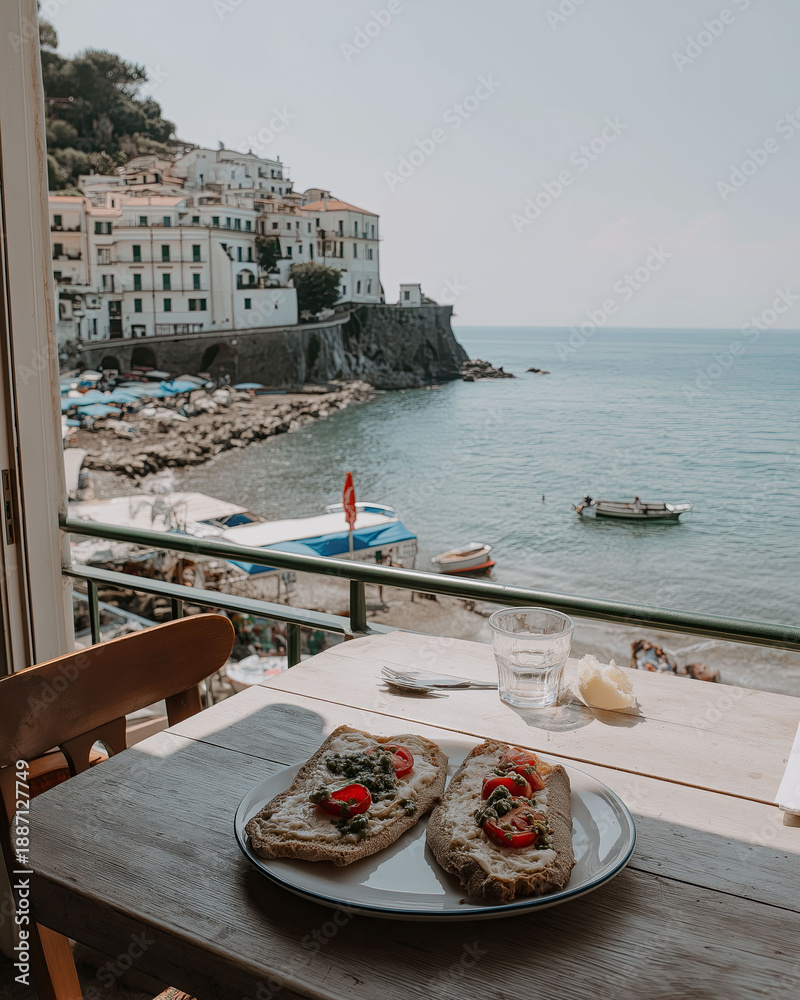 Fototapeta premium An open-faced sandwich meal is on a small table on a porch with a coastal vista.