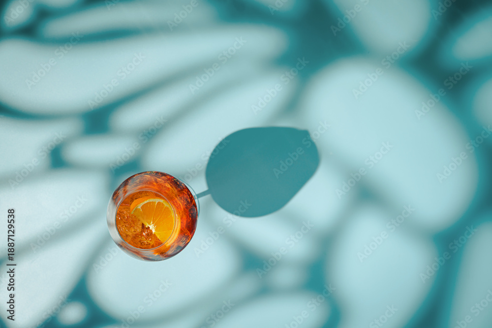 Fototapeta premium Summer refreshing cocktail aperol spritz on a blue background with shadows, top view