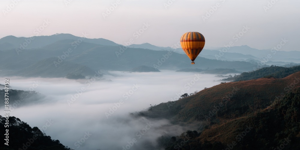 Obraz premium Vibrant hot air balloon over misty mountain landscape at sunrise