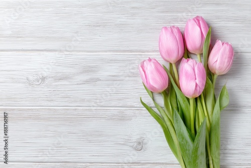 Pink tulips arranged against a rustic light wooden backdrop, with space for text