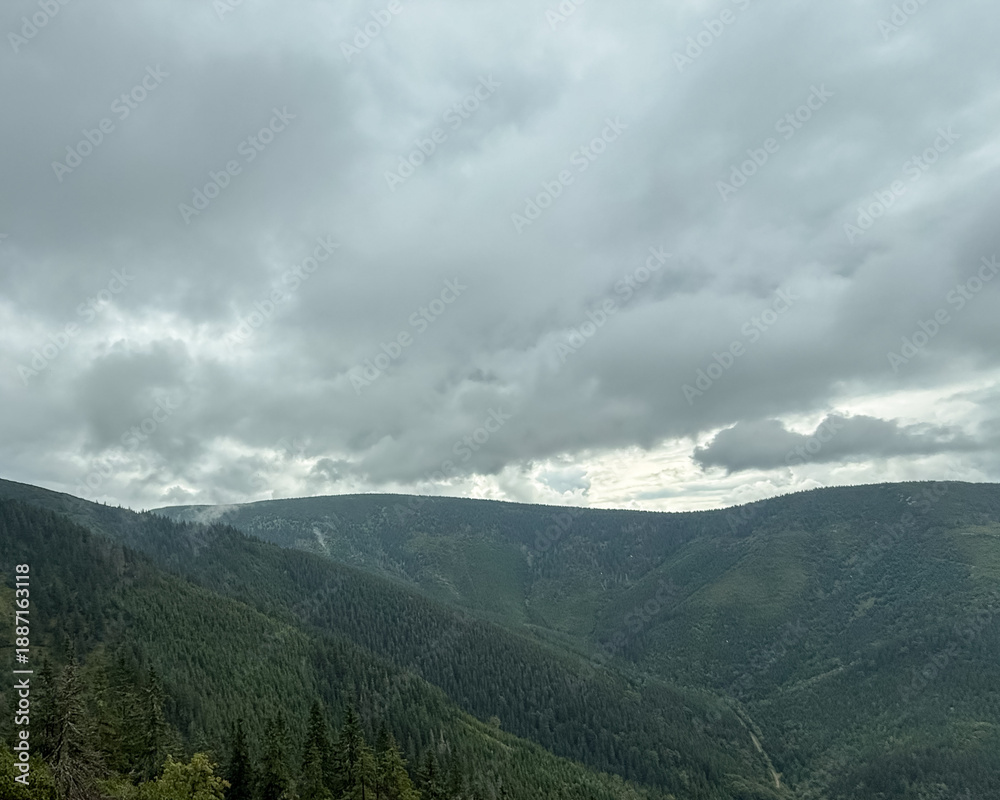 Obraz premium Moody mountain landscape with dark clouds and forested slopes
