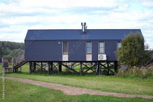 Fotografie Modern dark blue house elevated on stilts with large windows and air conditionin