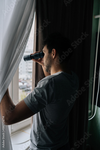 Foto Man curiously peering out window using monocular, watching with intense emotion