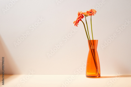 Quadro su tela Minimalist Still Life with Orange Gerbera Flowers in Glass Vase