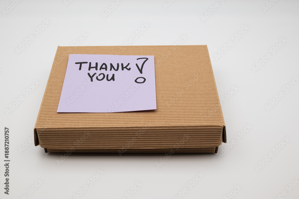 Obraz premium Cardboard box with purple sticky note saying THANK YOU on white background.