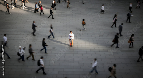 Crowd of people walking on city sidewalk with one person standing still
