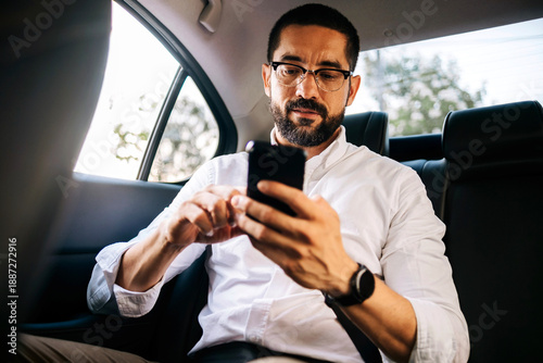 Business man using smartphone while commuting in car