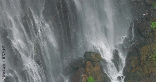 Close-Up Detail of Tumpak Sewu Waterfall Cascading Over Mossy Cliff, Indonesia