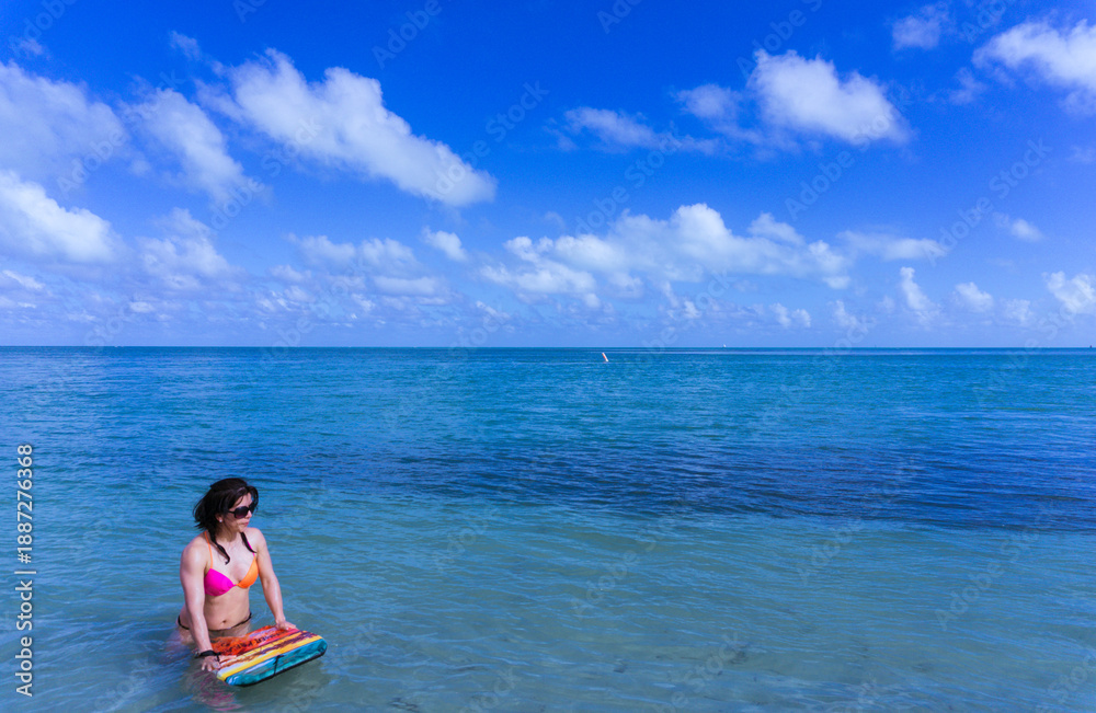 Fototapeta premium A woman is sitting on a surfboard in the ocean