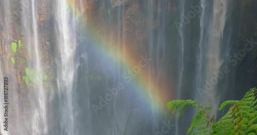 Close-Up Detail of Tumpak Sewu Waterfall with Rainbow Over Mossy Cliff, Indonesia