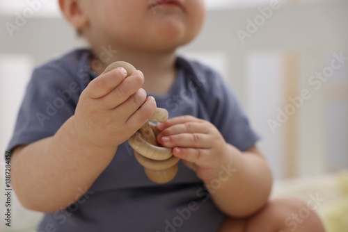 Bild auf Leinwand Cute little baby with wooden rattle at home, closeup