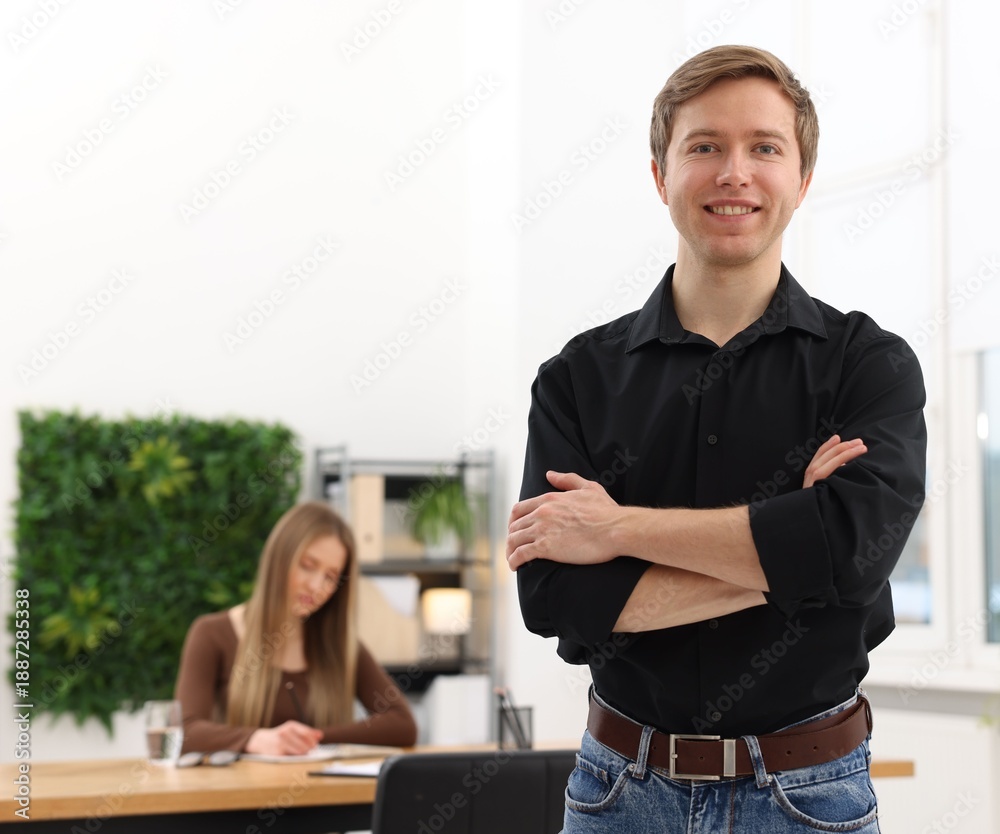 Fototapeta premium Portrait of smiling recruiter with crossed arms and candidate in office, selective focus. Space for text