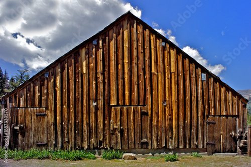 Slika na platnu Old Barn with rough-hewn wood planks, adjacent to alpine meadow, central Sierra