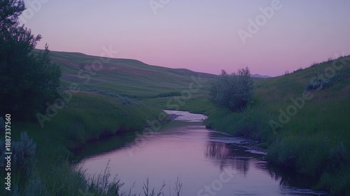 Gentle stream winds through a grassy valley at twilight.