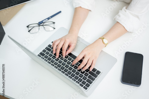 Top-view images of an Asian woman using a laptop keyboard on an office desk.