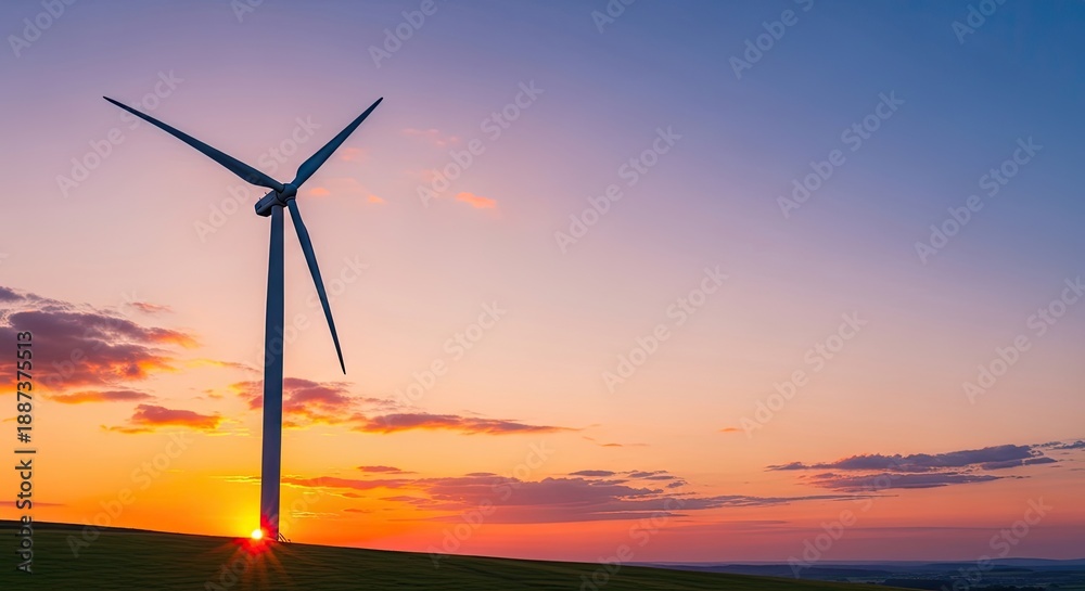 Obraz premium A wind turbine stands tall against a vibrant sunset sky, casting a silhouette against the horizon.