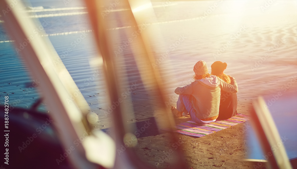 Fototapeta premium Couple, hug and relax at beach on vacation, holiday and travel on road trip together with back view. Embrace, man and woman on blanket by ocean for love, adventure and getaway in summer with sunshine